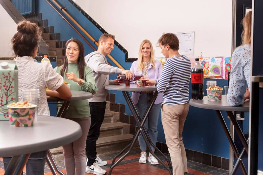 Mensen die genieten van een sociale bijeenkomst met statafels in een moderne locatie.