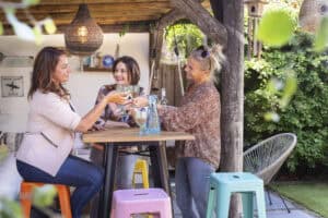 Vrouwen genieten van drankje op een statafel in tuin.